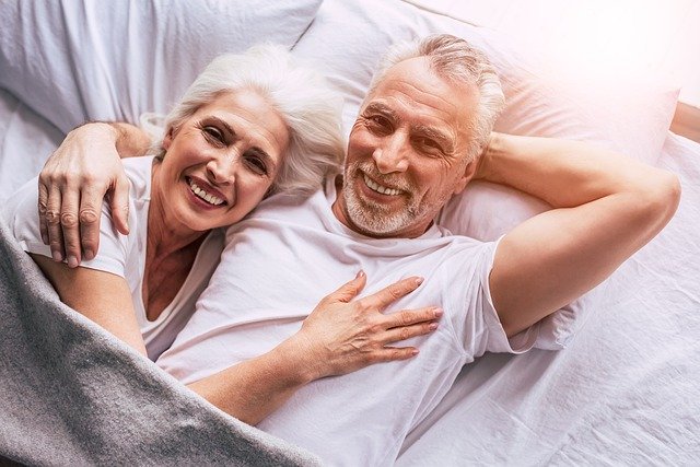 Manželský pár v důchodovém věku ležící v posteli.